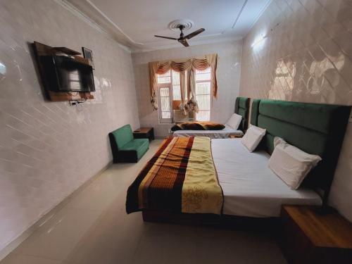 a bedroom with two beds and a couch and a tv at Pratap Resort in Katra