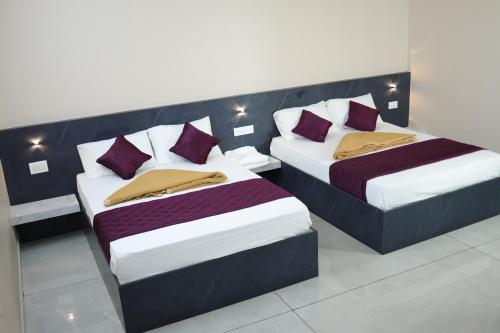 two beds in a room with purple and white pillows at RUBY Residency in Palni