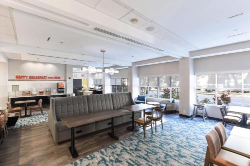 a waiting room with a couch and tables and chairs at Hampton Inn Miami-Coconut Grove/Coral Gables in Miami