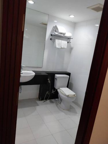 a bathroom with a toilet and a sink and a mirror at Nana Hiso Hotel in Bangkok