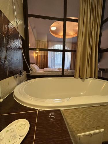 a bath tub in a bathroom with a large window at Hotel Artimino in Timişoara
