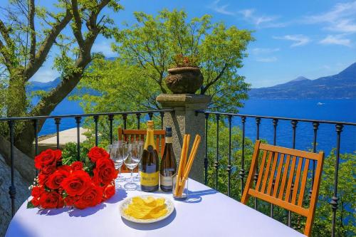 a table with wine glasses and flowers on a balcony at Villa Lucia Varenna in Varenna