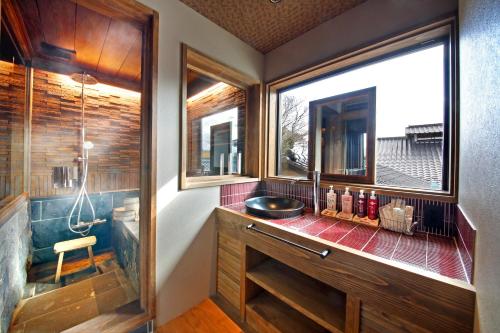 a bathroom with a shower and a sink and a window at Yunoyado Irifune in Aso