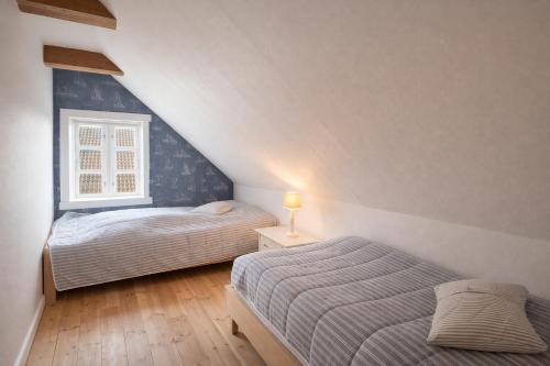 two beds in a attic bedroom with a window at The Cozy Cottage in Hirtshals