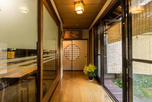 einen Flur mit Glastüren, einem Tisch und Blumen in der Unterkunft Kamuroan in Kyoto