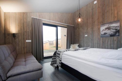 une chambre avec un lit, un canapé et une fenêtre dans l'établissement Arnarstapi Cottages, à Stapi