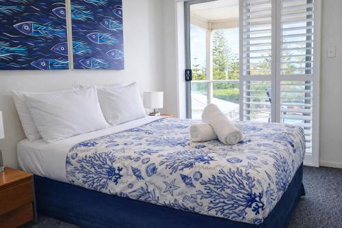 a bedroom with a blue and white bed with a window at Scarborough Beach Front Resort - Shell Seven in Perth