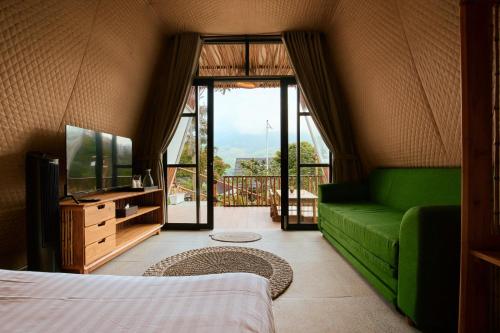 a living room with a green couch and a television at Luxcamp Selo - Merapi View by Horison in Selo