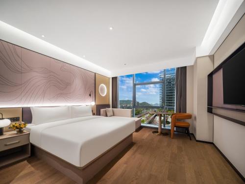 a hotel room with a bed and a television at Maison New Century Ninghai Railway Station in Ninghai
