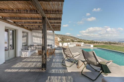 a patio with chairs and a swimming pool at Lolantonis - 3BR Sea View & Infinity Pool - Thymari in Aspro Chorio Paros