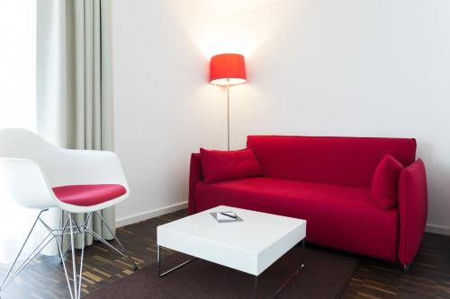 a living room with a red couch and a white table at Grimm's Berlin Mitte in Berlin