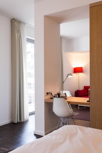 a hotel room with a desk and a red couch at Grimm's Berlin Mitte in Berlin