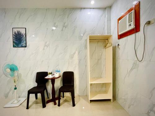a room with two chairs and a table and a shower at Arriyus Apartelle in Maya