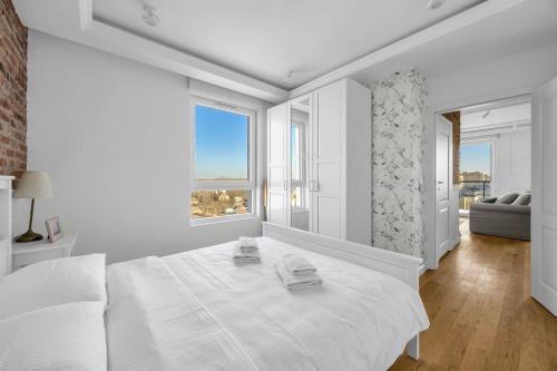 a white bedroom with a large bed and a large window at Mehoffera Superior Apartment by BookingHost in Warsaw