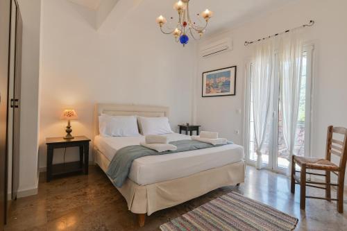 a white bedroom with a bed and a chandelier at Citron, Parga Center Residence in Parga