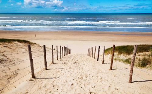 a beach with a fence in the sand and the ocean at Kitty's Place Warmond in Warmond