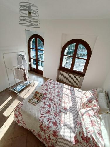 a bedroom with a large bed and two windows at La Casa del Merlo in Rodello
