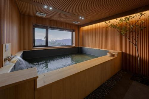 a large bath tub in a room with a window at Mandeok Denbasta Ryokan in Busan