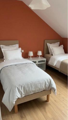 a bedroom with two beds and two tables with lamps at La parenthèse Jurassienne in Orgelet