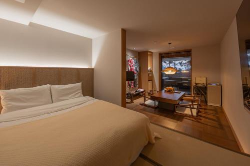 a bedroom with a bed and a desk and a window at Mandeok Denbasta Ryokan in Busan
