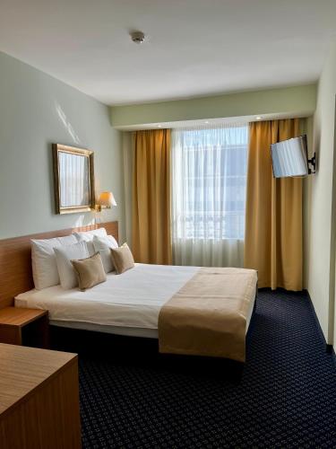 ein Hotelzimmer mit einem großen Bett und einem Fenster in der Unterkunft Hotel Monogram Park in Ruma