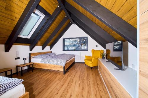 a attic bedroom with a bed and a yellow chair at Apartmány U Kovárny in Horní Blatná