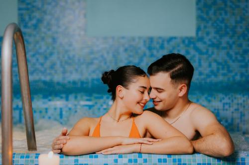 a man and a woman in a swimming pool at Hotel O3zone - Mountain Spa & Conference in Băile Tuşnad