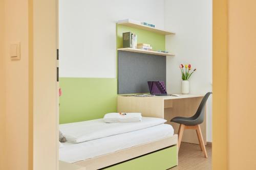 a room with a bed and a desk with a chair at I AM HOTELS Leoben in Leoben