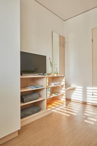 a room with a flat screen tv in a white wall at I AM HOTELS Leoben in Leoben
