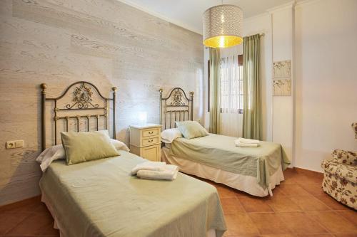a bedroom with two beds and a chandelier at Casa Sofia in Ubrique