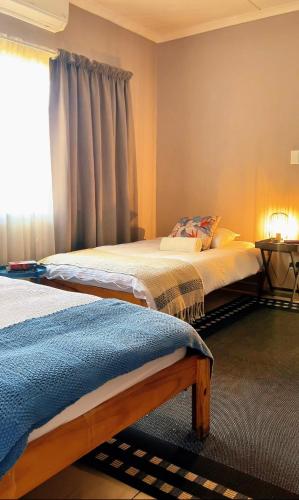 due letti in una stanza con finestra di Pangolin self-catering accommodation a Windhoek