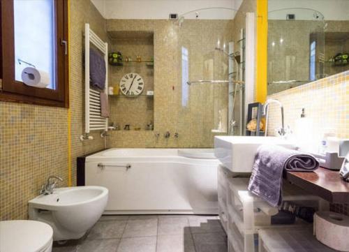 bagno con vasca, lavandino e orologio di Romantic Apartment Porta Venezia a Milano