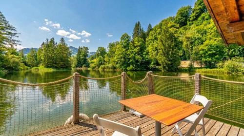a wooden table and chairs sitting on a dock next to a lake at Tiny Water Villa on a Lake with shared camping bathroom in Zweisimmen