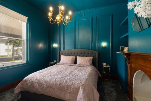 a blue bedroom with a bed and a chandelier at Wallace Cottage in Mount Gambier