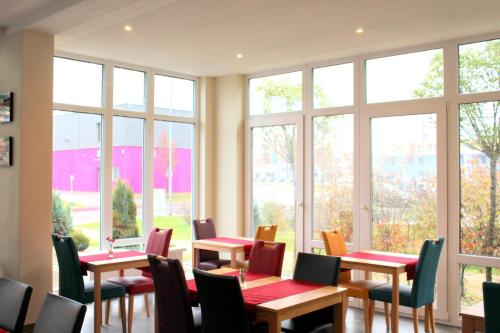 a room with tables and chairs and windows at Come IN Hotel in Ingolstadt