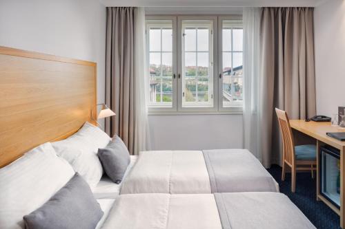 a hotel room with a bed and a desk and window at Hotel Clement in Prague