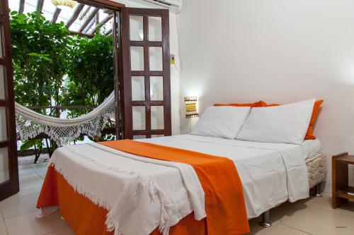 1 dormitorio con 1 cama con manta naranja y blanca en Pousada Barra Vento, en Morro de São Paulo