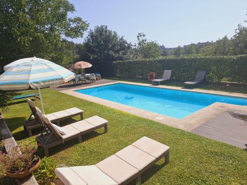 a swimming pool with lounge chairs and an umbrella at CASA DA TIA ROSA in Fiscal