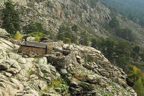 a building on the side of a rocky mountain at L'Acqua Viva in Calacuccia