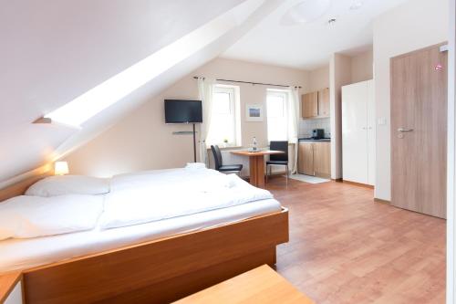 1 Schlafzimmer mit einem großen weißen Bett und einer Küche in der Unterkunft Airport Hotel One Aparthotel Sylt in Tinnum