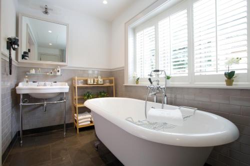 a bathroom with a tub and a sink and a window at Hurley House Hotel in Hurley