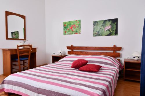 a bedroom with a bed with two red pillows on it at apartmani Novotny crveni in Banjol