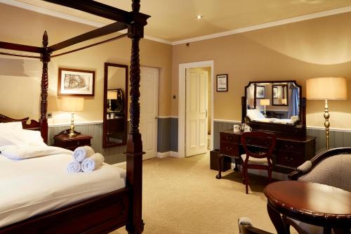 a bedroom with a bed and a desk and a mirror at The Golden Pheasant in Knutsford