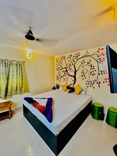 a bedroom with a bed with a tree mural on the wall at Sun India Guest House in Howrah