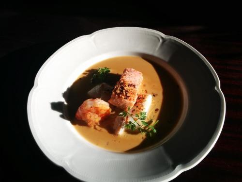 a white plate with a bowl of soup on a table at Sevel Kro in Vinderup