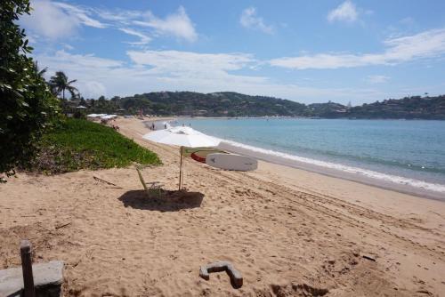 a beach with a surfboard on the sand and the ocean at Villa Ferradura Mar in Búzios