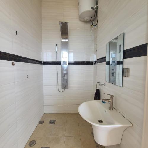 ein weißes Badezimmer mit Waschbecken und Dusche in der Unterkunft La vila viollette in Kigali