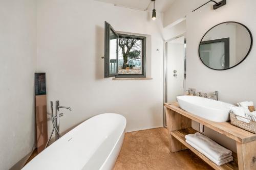 a bathroom with a tub and a sink and a mirror at Salcheto WineHouse in Montepulciano