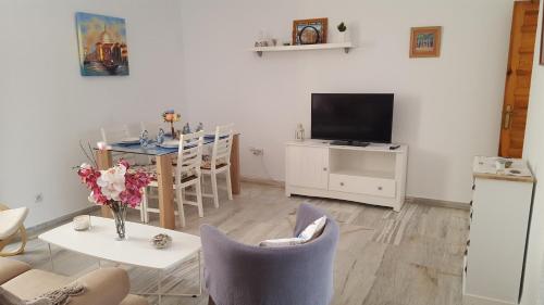 een woonkamer met een televisie en een tafel met stoelen bij Casa Típica Cordobesa in Córdoba
