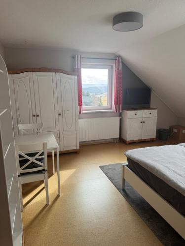 a bedroom with a bed and a desk and a window at Ferienzimmer Schürer in Lauter